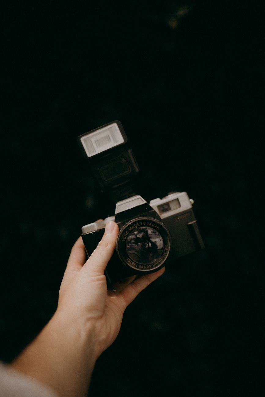vintage film camera held in hand against dark background